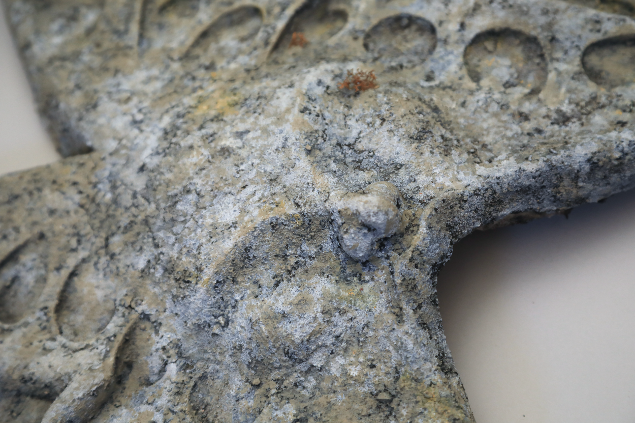 Latex stone headpiece shaped like two winged forms joined at the center, each containing a small sculpted baby figure in relief. The piece covers the wearer’s head and face, merging organic and mechanical forms.