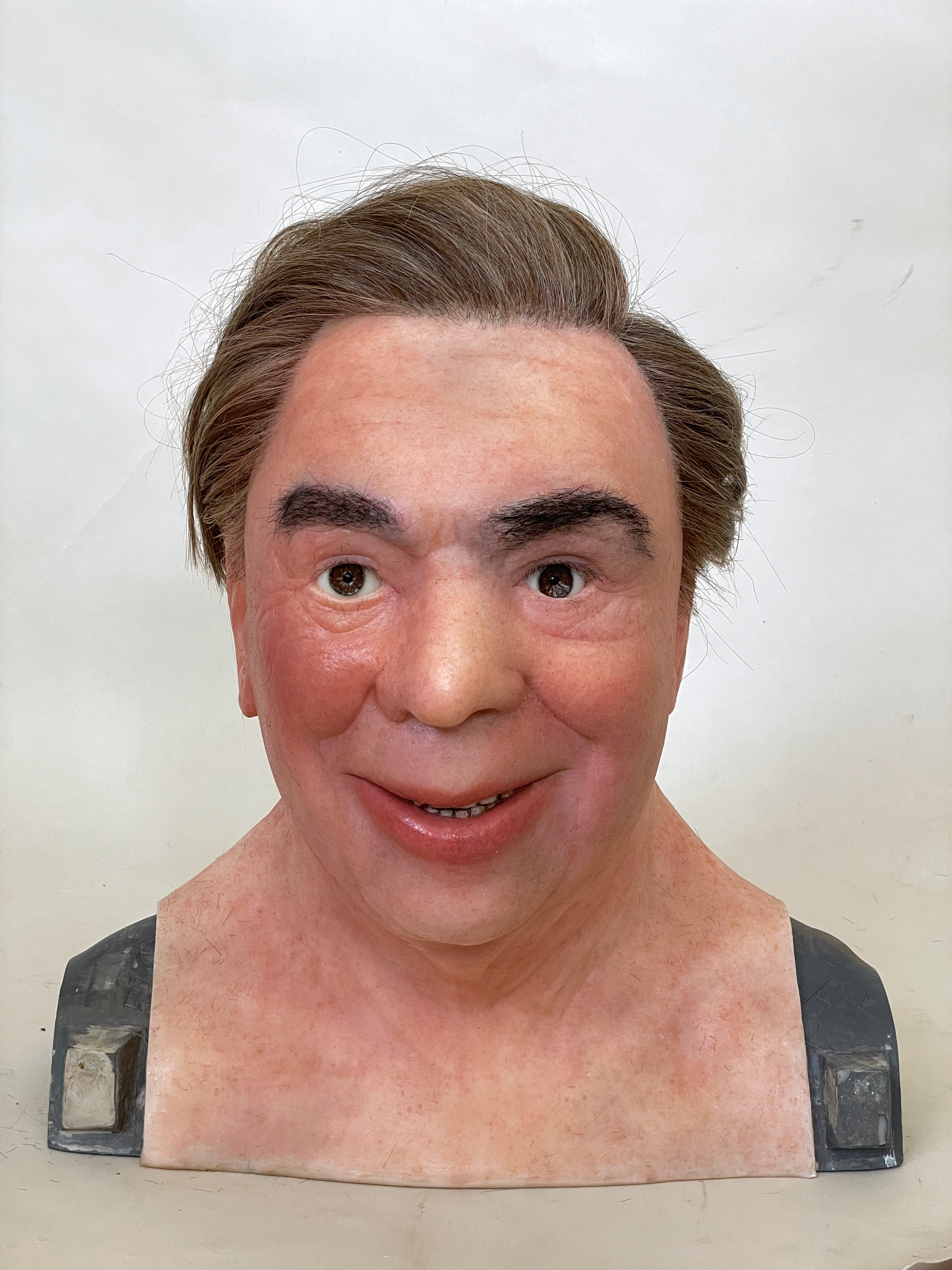 Silicone mask sculpture resembling a lifelike human head with a smiling expression, part of the work “Salieri,” a wearable prosthetic used in performance.